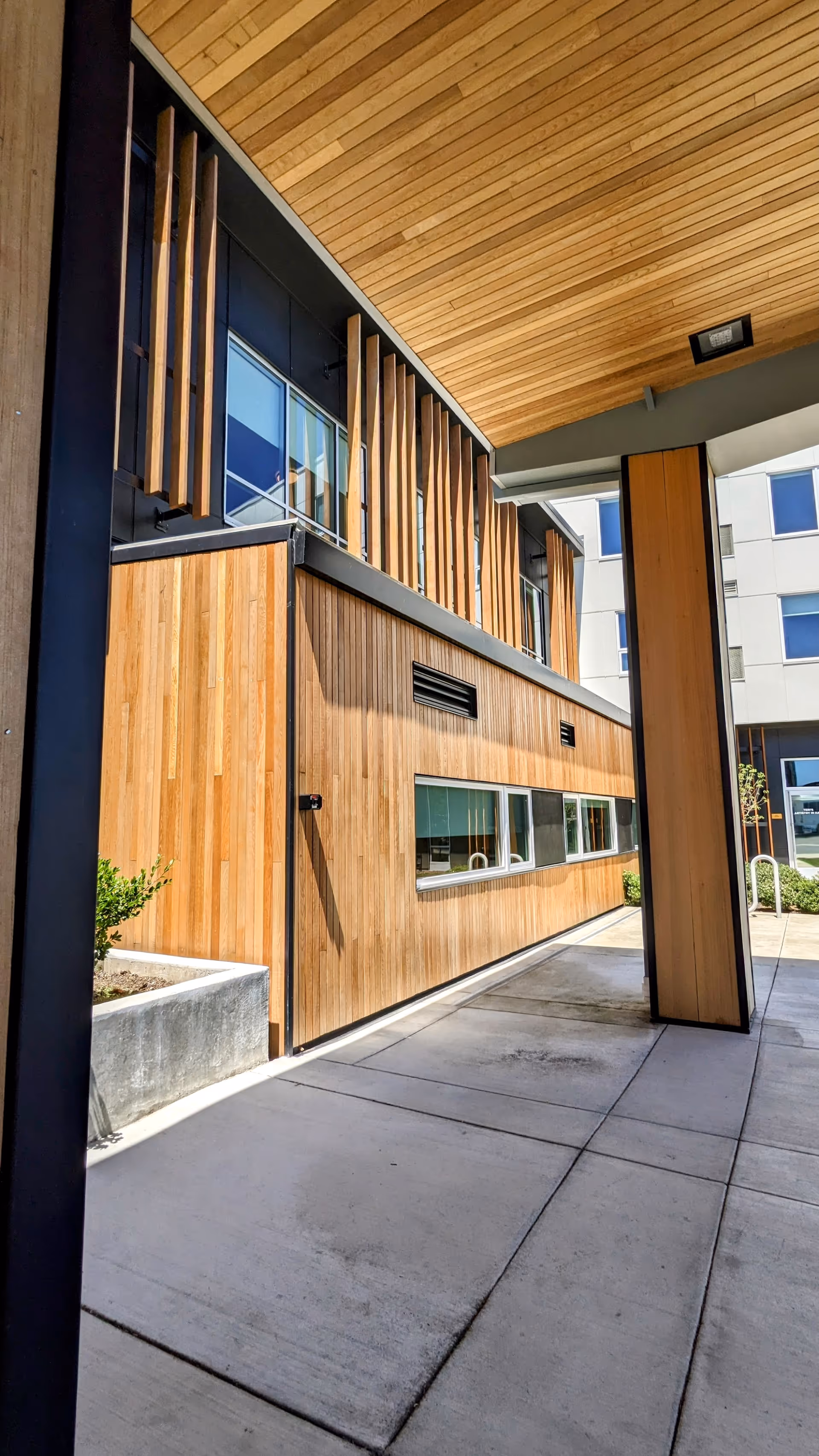 Modern wooden exterior facade of The Ackerly at Reed’s Crossing with a covered entrance.