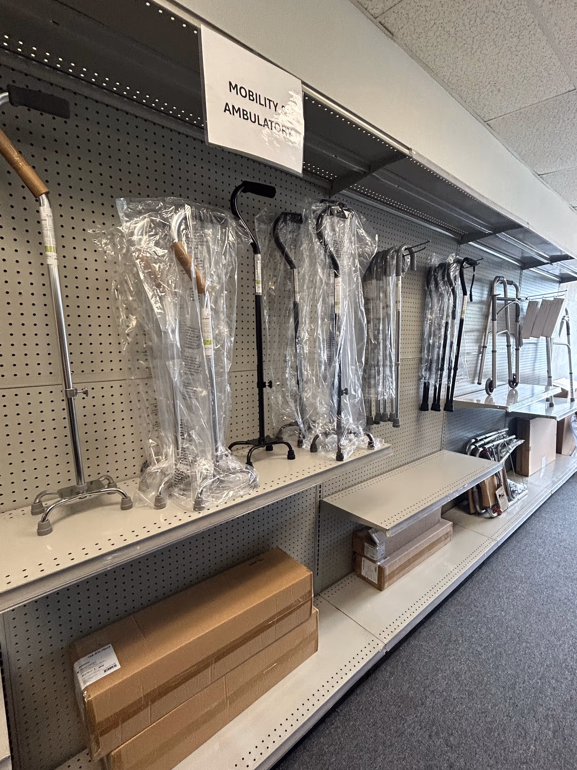 Display of mobility aids and canes along pegboard shelves in an indoor supply area.