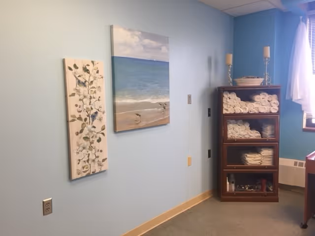 Interior of a light blue room with wall art and a towel shelf.