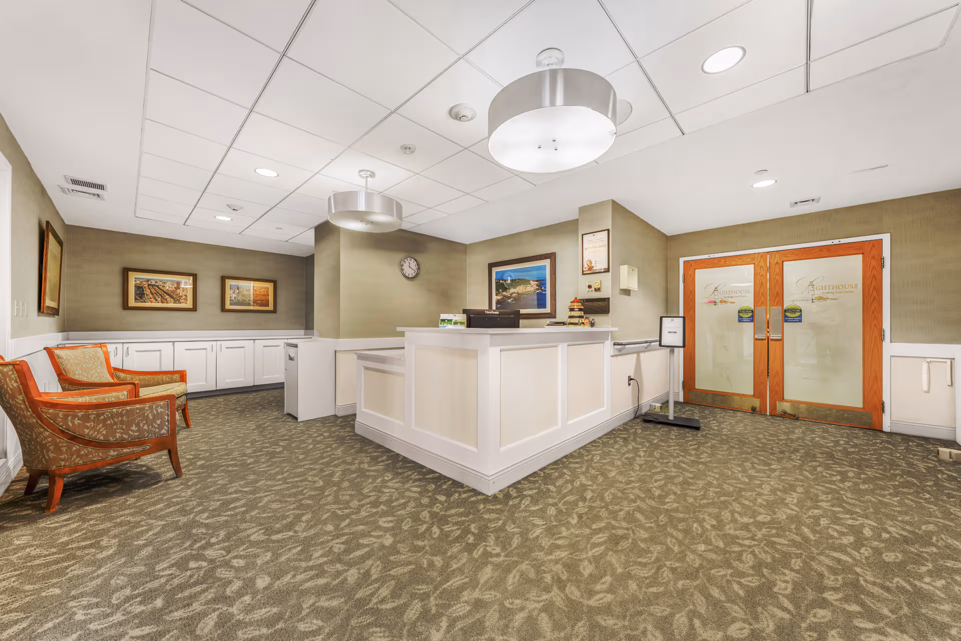 Bright interior lobby with white reception desk, seating area, and double glass doors.