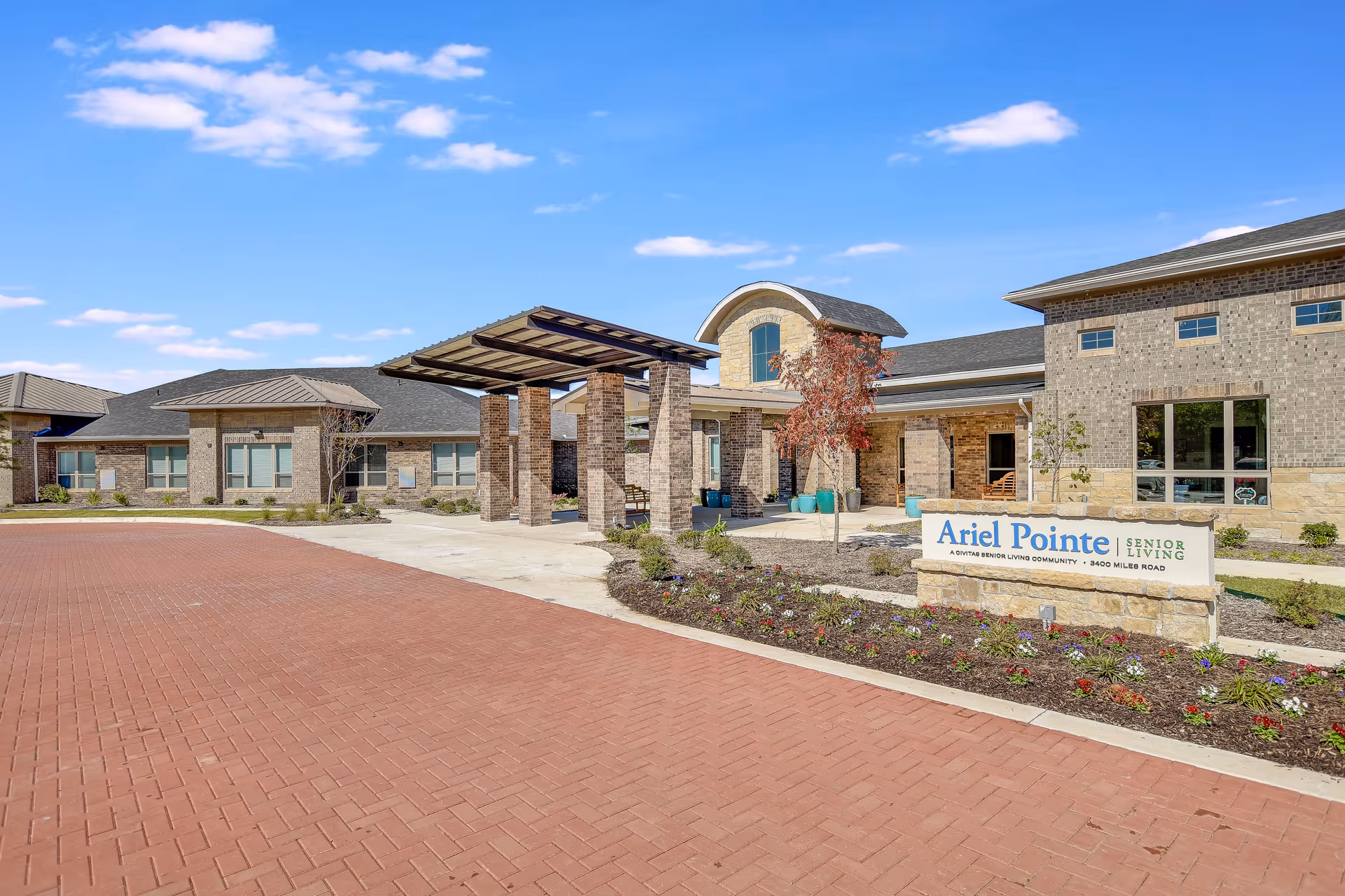 Exterior view of Ariel Pointe of Sachse Senior Living with brick building and entrance canopy.
