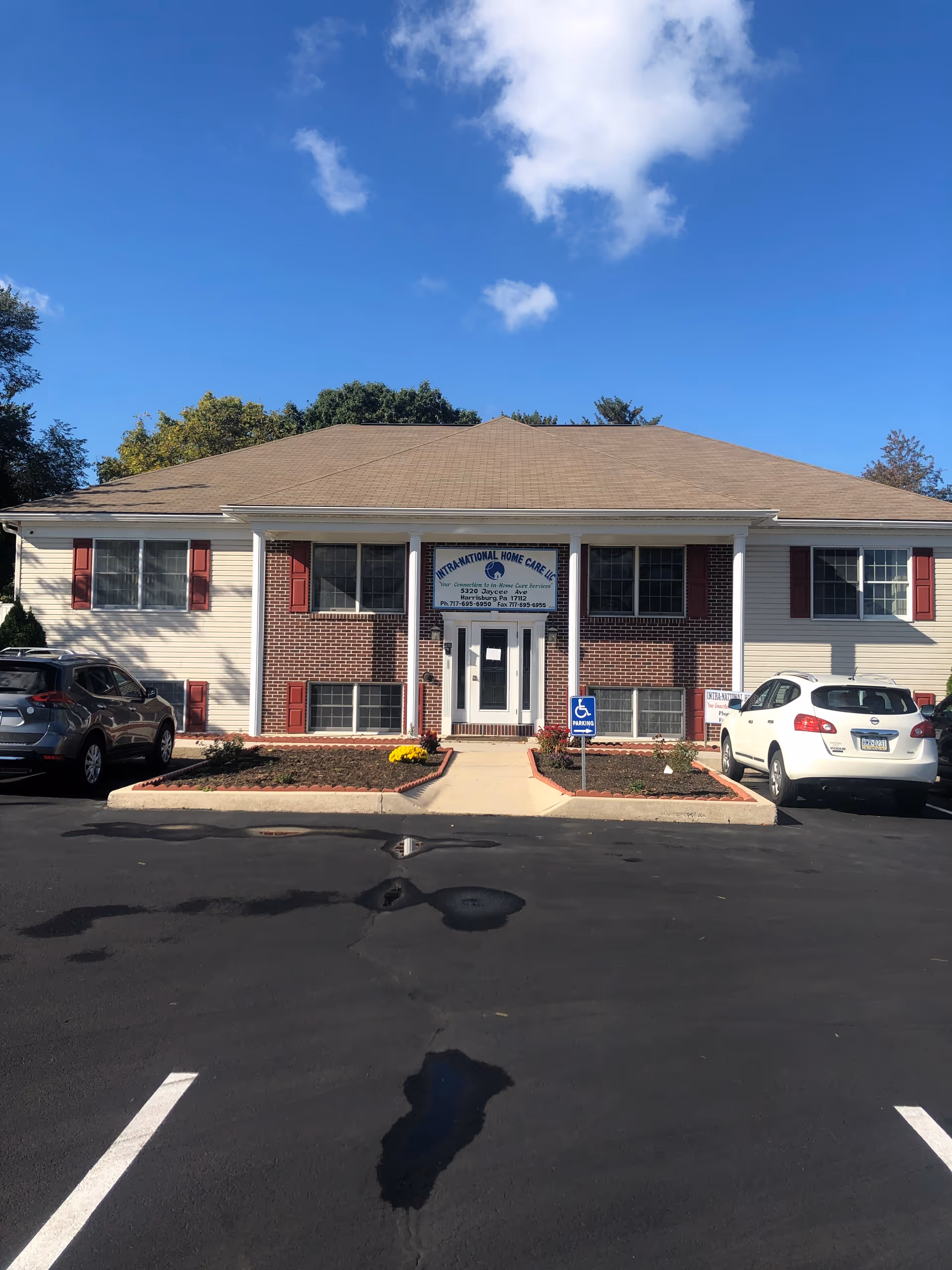 Front view of INTRA-NATIONAL HOME CARE, LLC facility with parked cars and a sign.