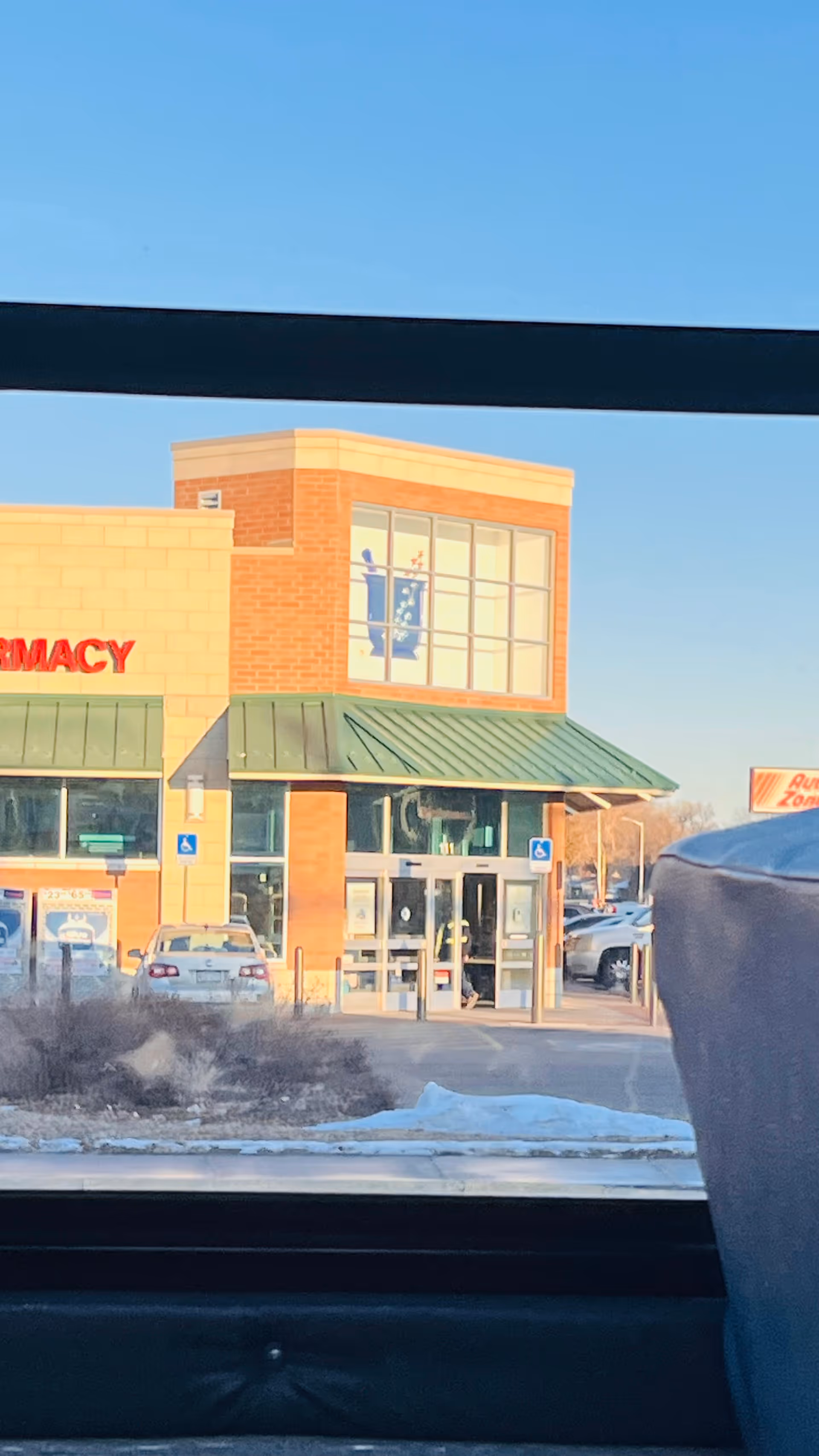 Front view of a brick medical center with a pharmacy storefront and glass doors.