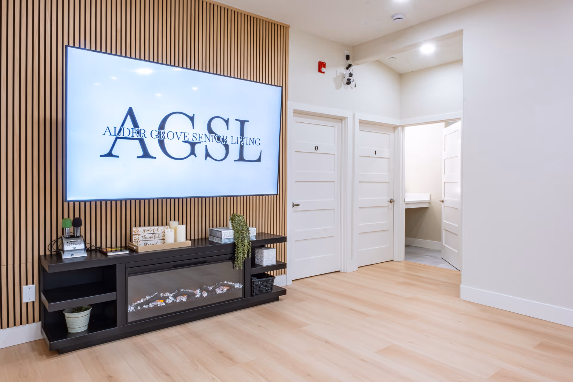 Lobby area with a large AGSL Alder Grove Senior Living sign on a wooden slat wall.