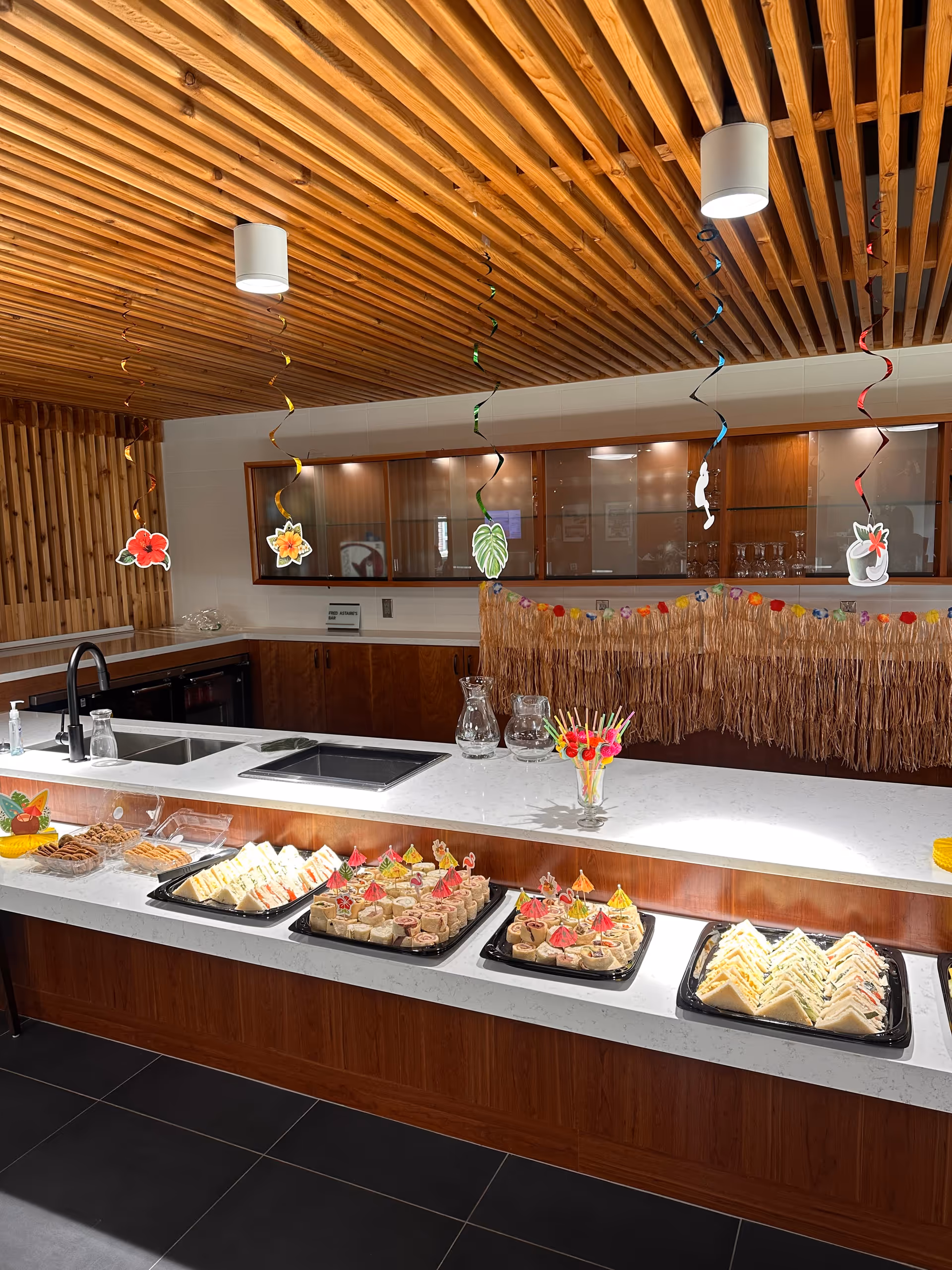 A modern kitchen counter displays pastries and drinks under a wooden beamed ceiling with decorations.