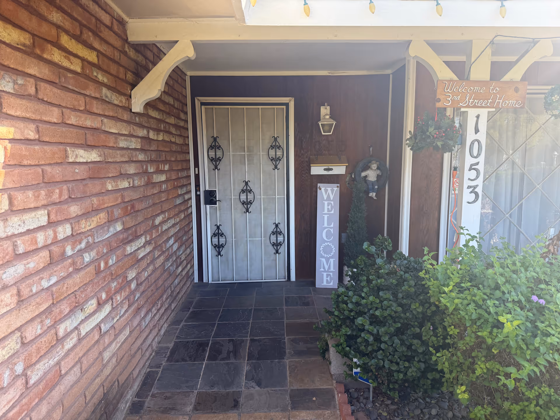 Front brick entrance of Third Street Home with decorative door and welcome sign.