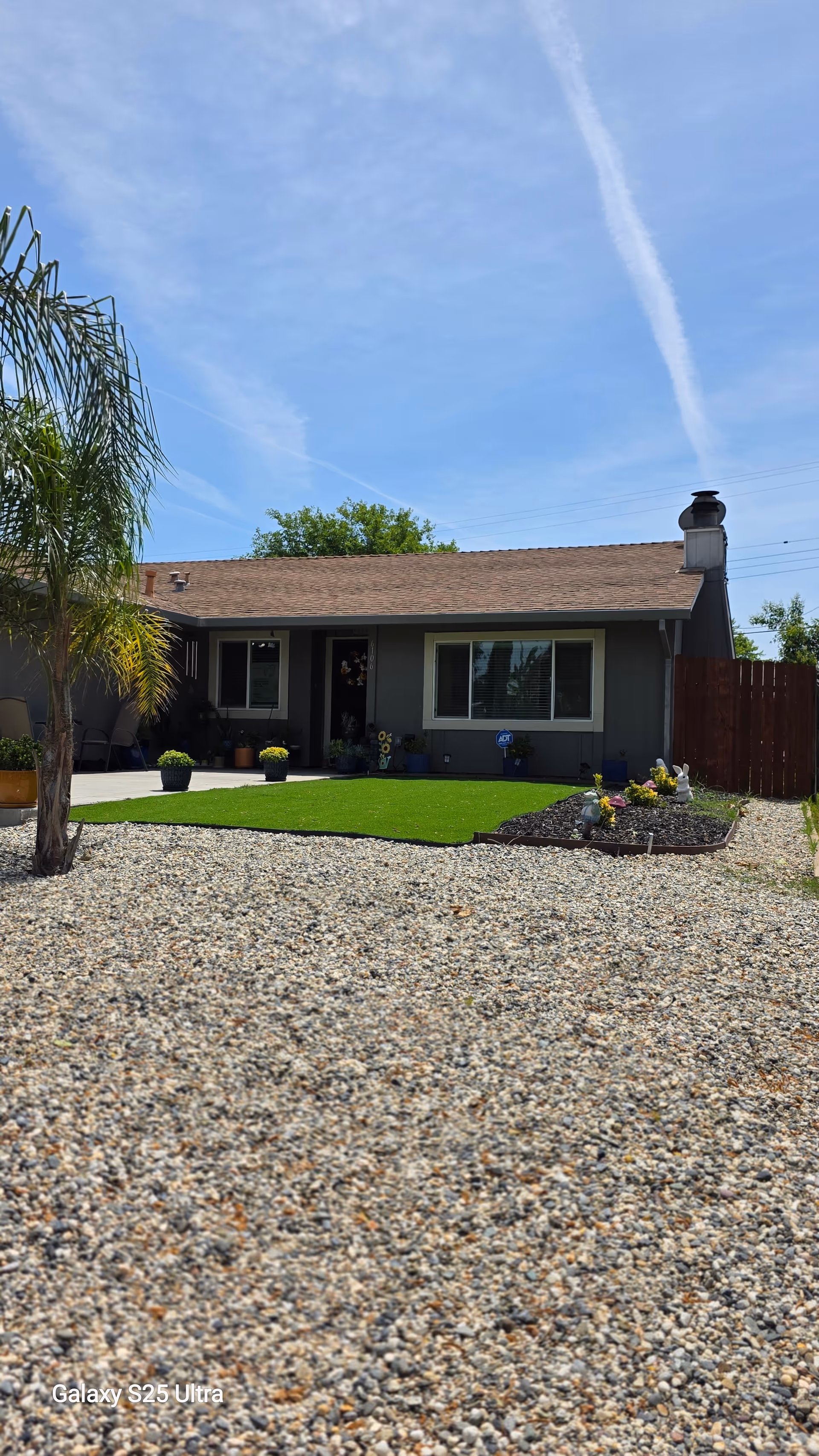 Single story gray house with gravel front yard and small lawn in foreground.