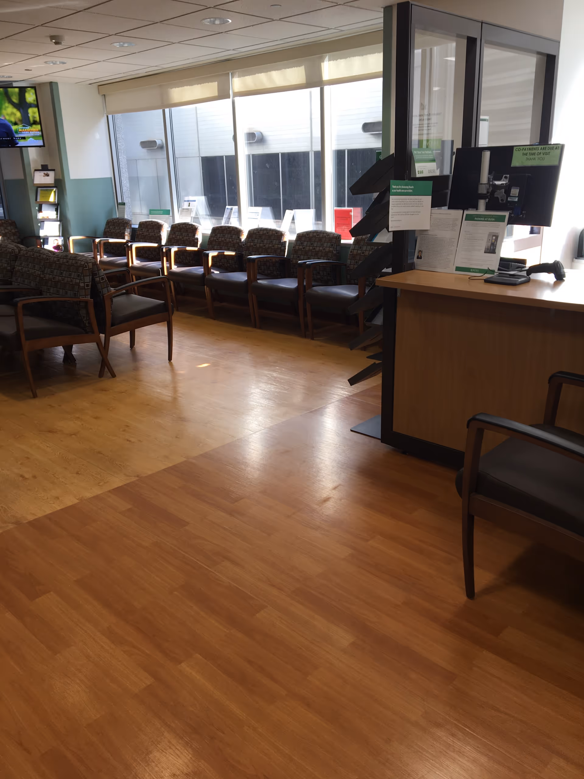 Empty waiting lounge with chairs along windows and a reception desk.