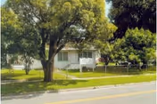 Exterior view of Lake Wire Retirement Center with trees, lawn, and a street in front.