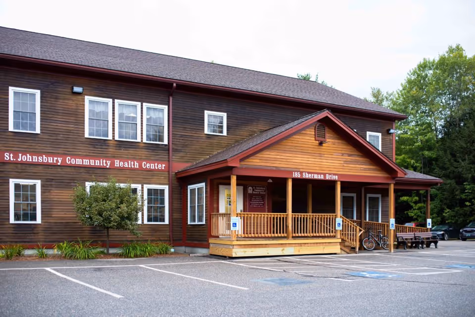 Exterior view of a wooden health center with a covered porch and parking lot.