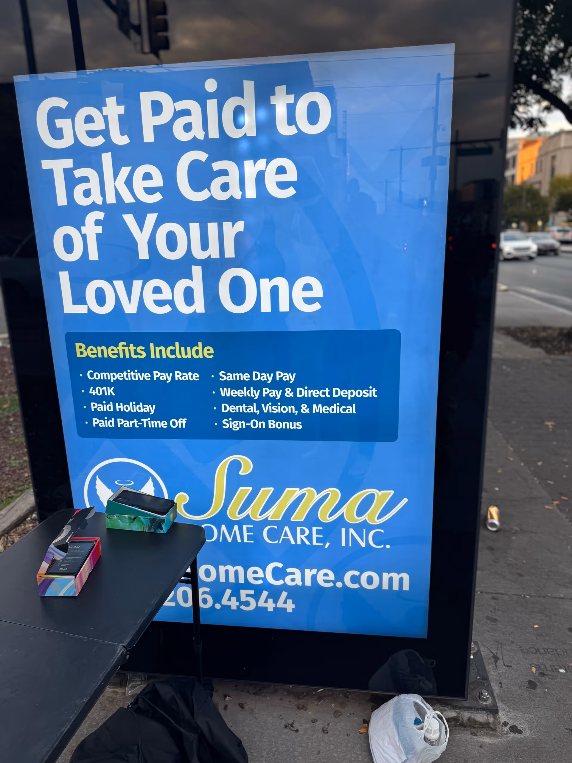 Large blue outdoor sign advertising caregiver jobs outside Suma Home Care, Inc.