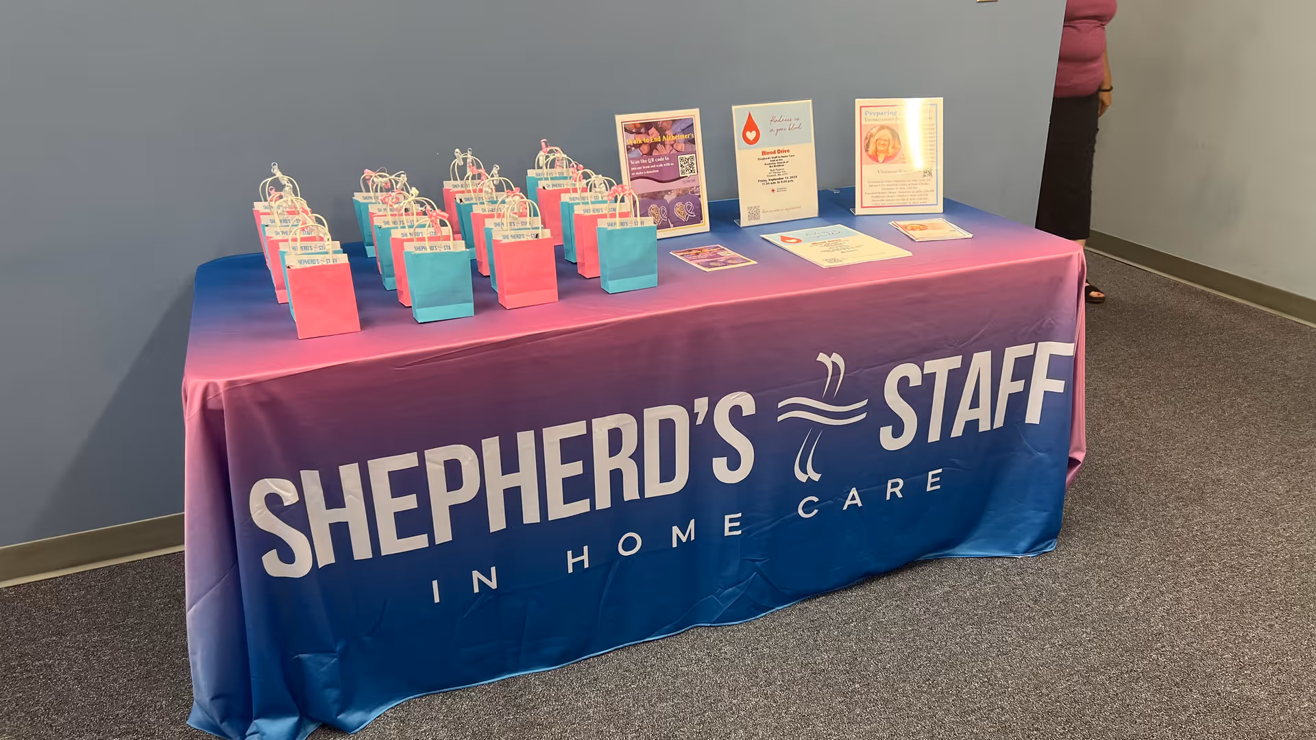 Table with gift bags and framed materials in a blue-walled interior for Shepherd's Staff In-Home Care.