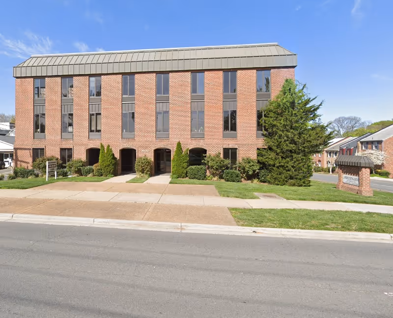 Brick senior living facility front with large windows and landscaped lawn.