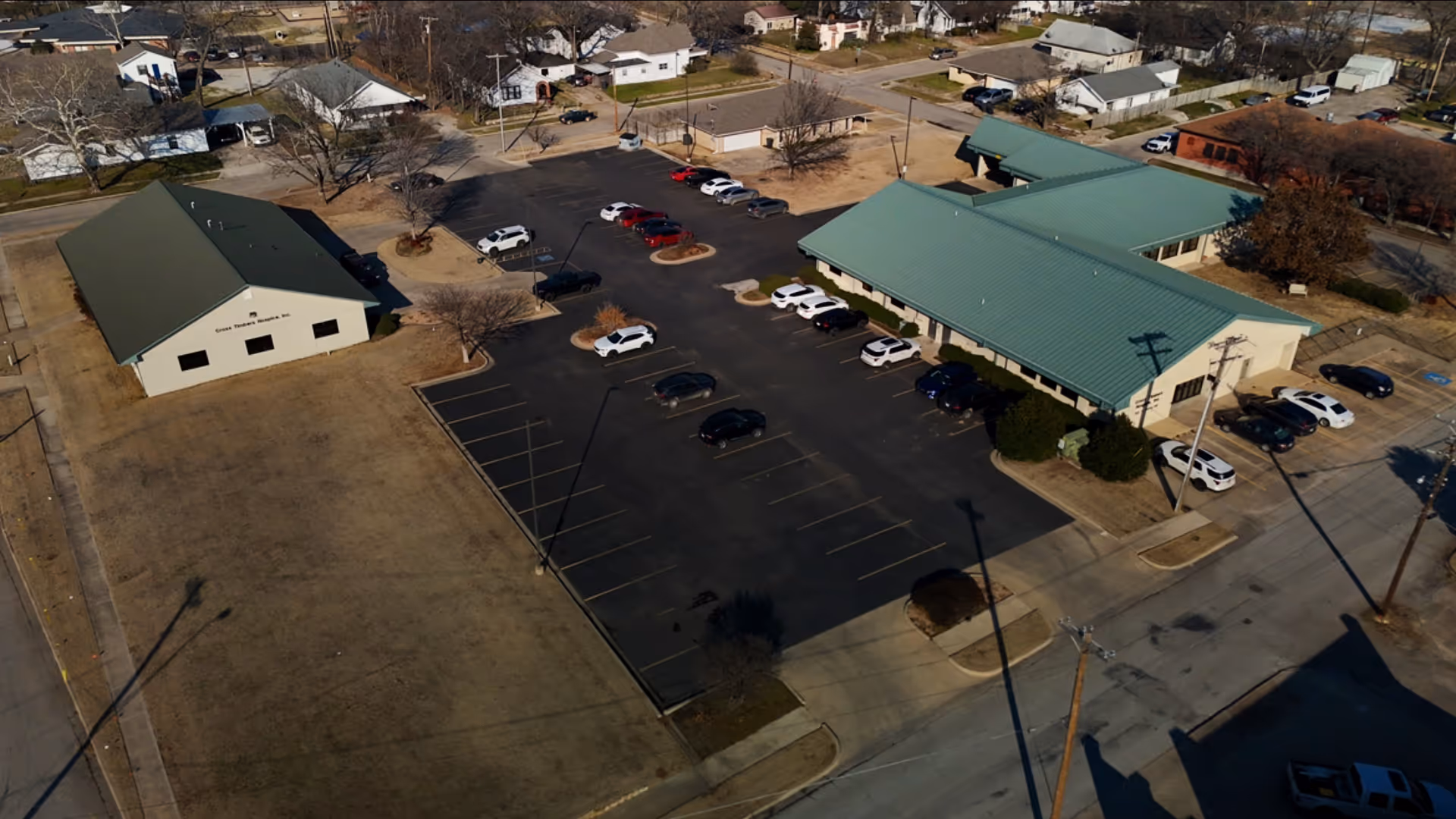 Aerial view of Cross Timbers Hospice Inc campus with green-roofed buildings and parking.