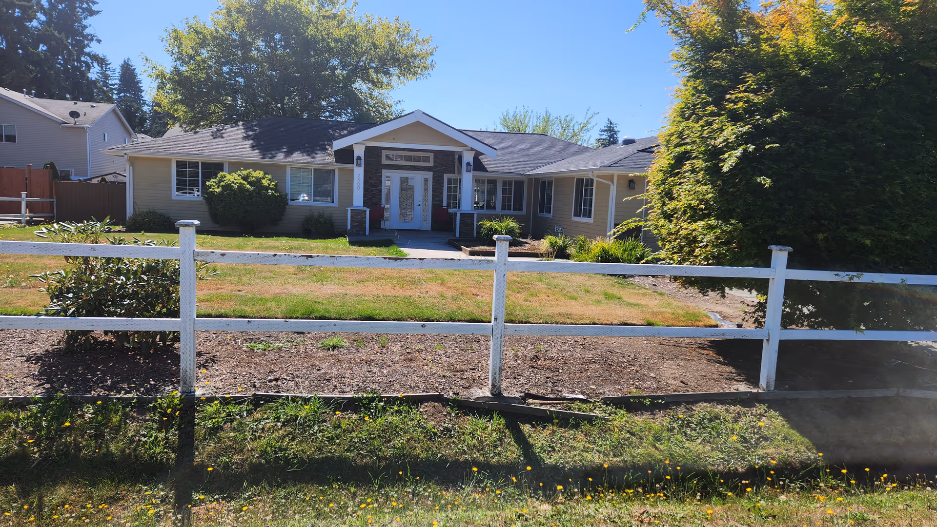 Mukilteo Green House exterior featuring a white fence and tidy front yard