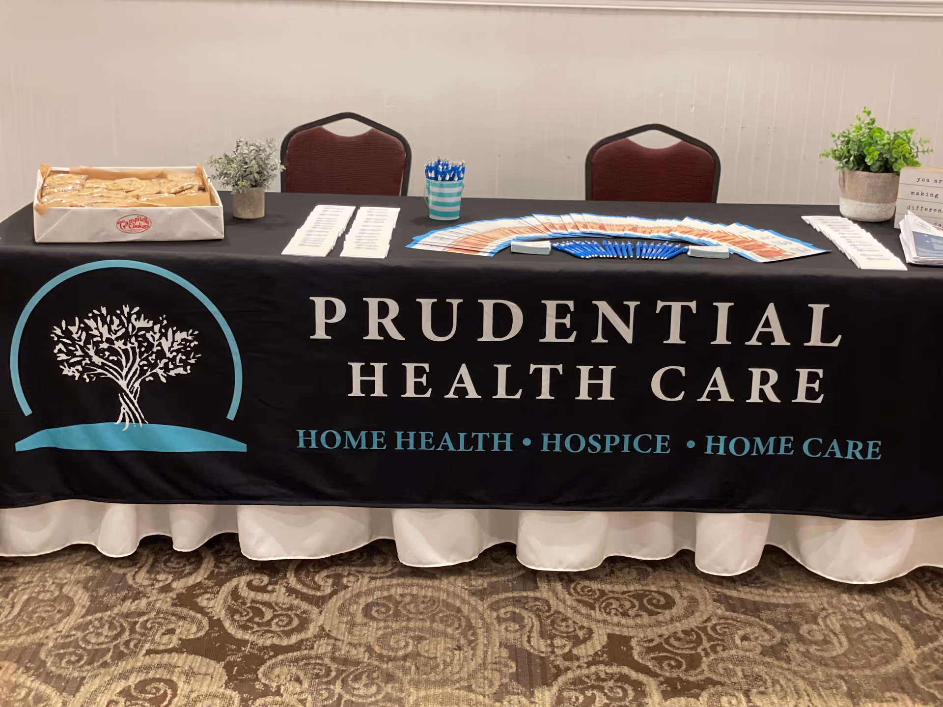 Indoors, a promotional table with Prudential Health Care banner and brochures.