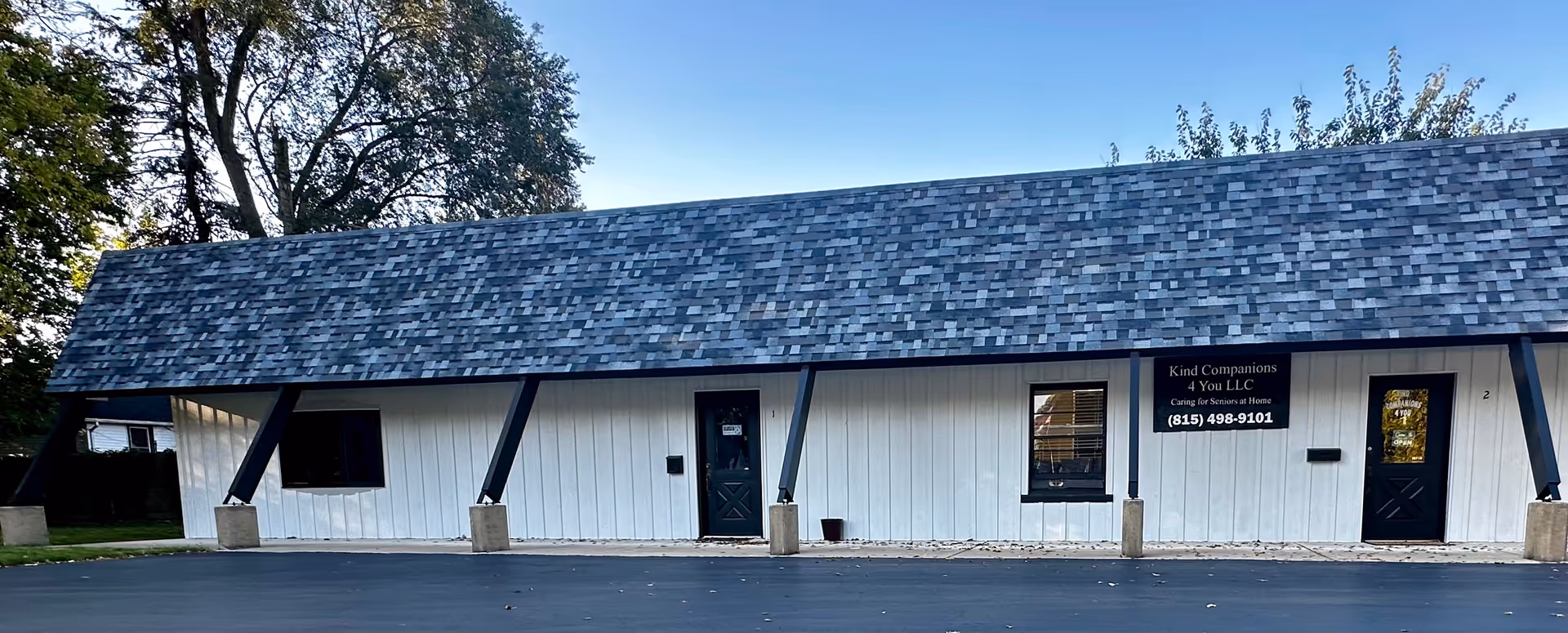 Exterior view of a single-story facility with a shingled roof and entrance signs.