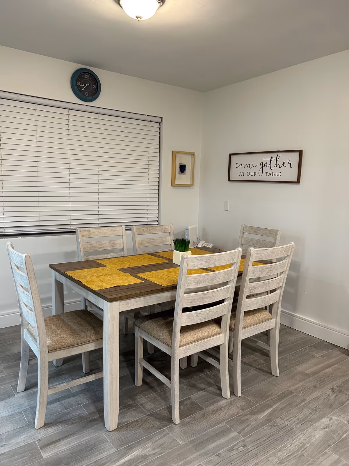 Light-filled dining room with a wooden table, six chairs, and wall decor.