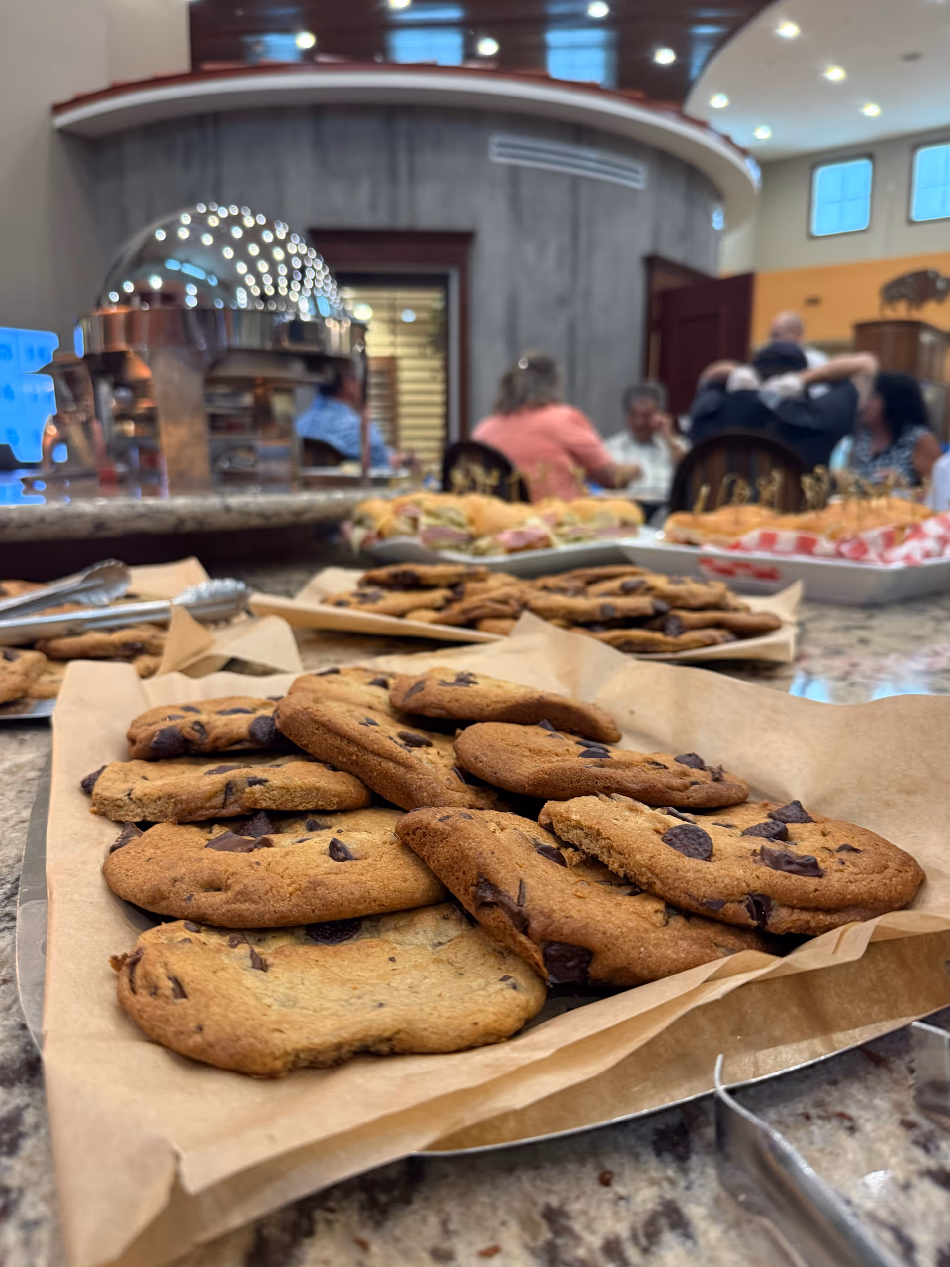 Tray of chocolate chip cookies on a counter, with residents socializing in the background.