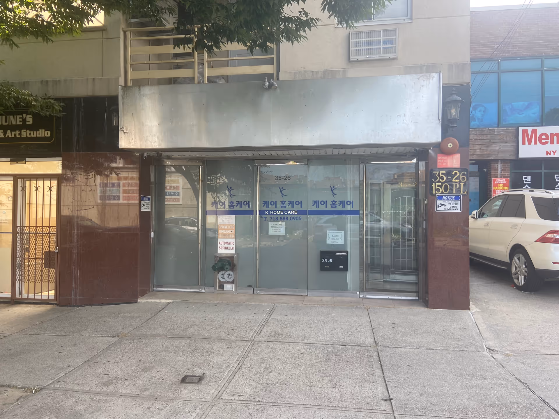 Storefront of K Homecare Corp on city sidewalk with glass doors and blue signage.