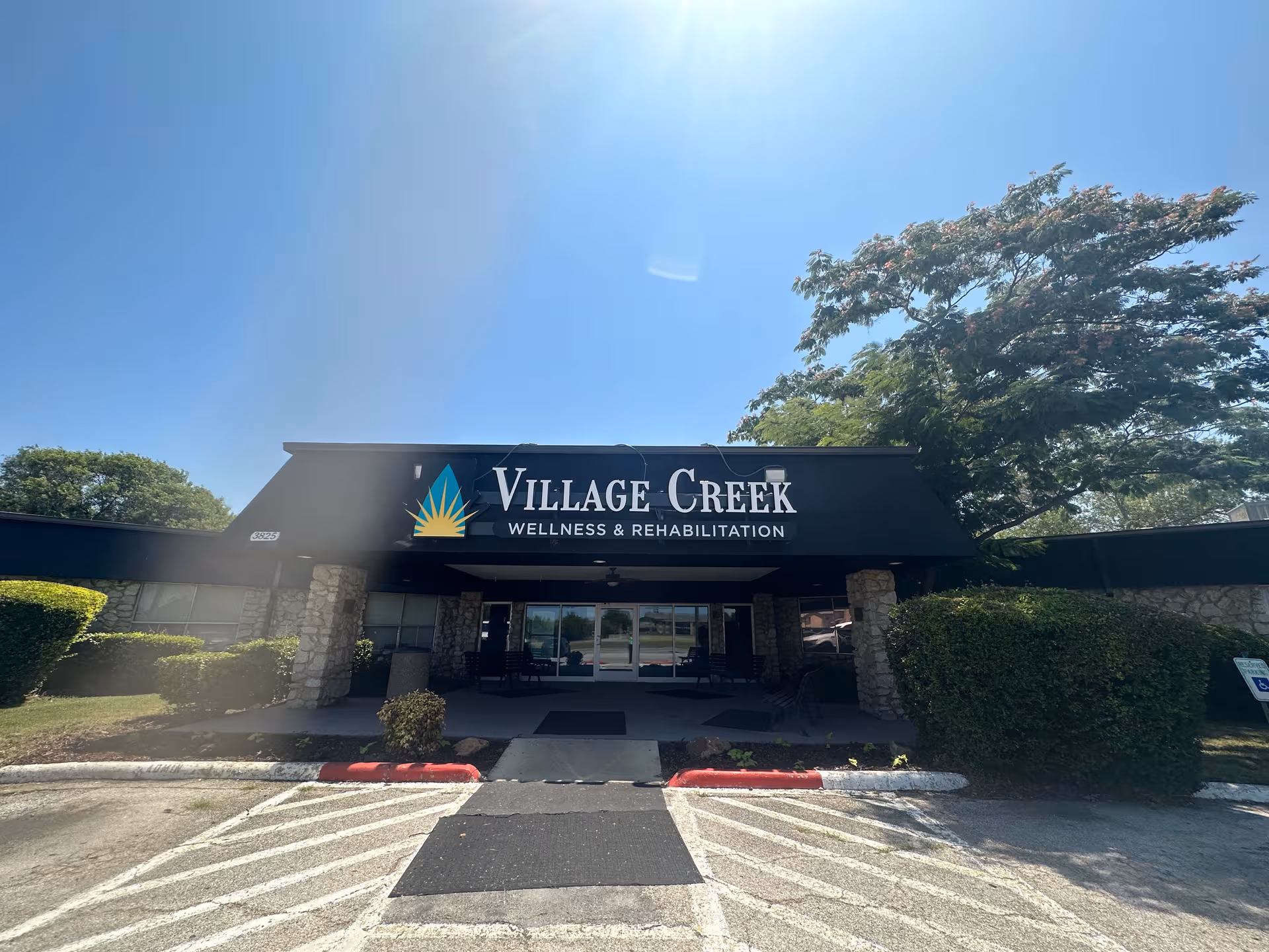 Front entrance of Village Creek Wellness and Rehabilitation with sign and trees