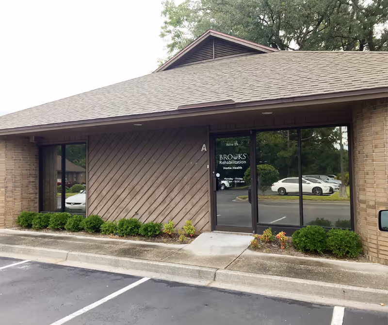 Front view of Brooks Rehabilitation Home Health entrance with parking and landscaping.