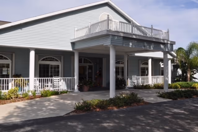 Front exterior of Arcadia Oaks Assisted Living with a welcoming porch and potted plants