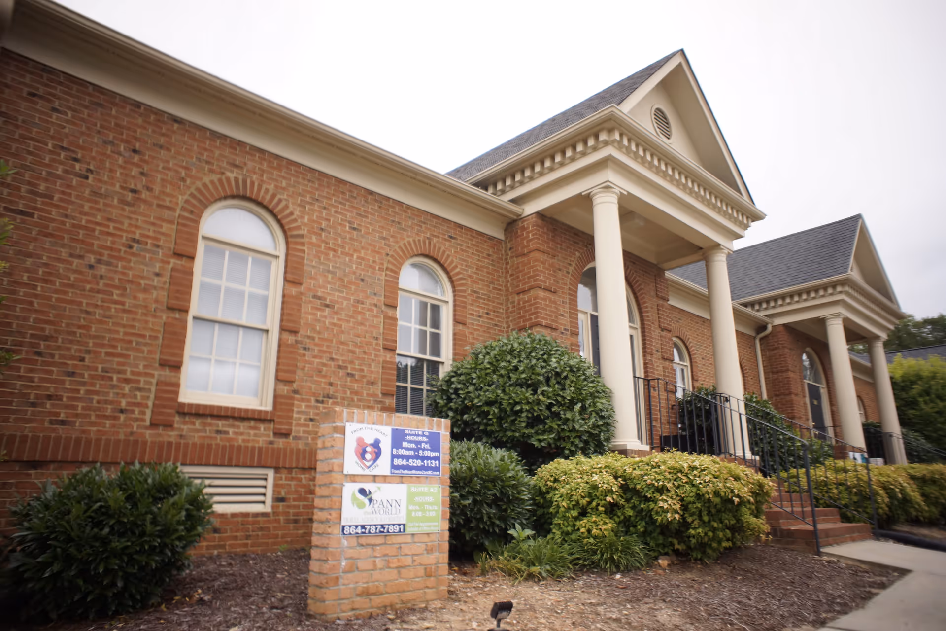 Brick senior living facility exterior with arched windows and prominent columns at the entrance.