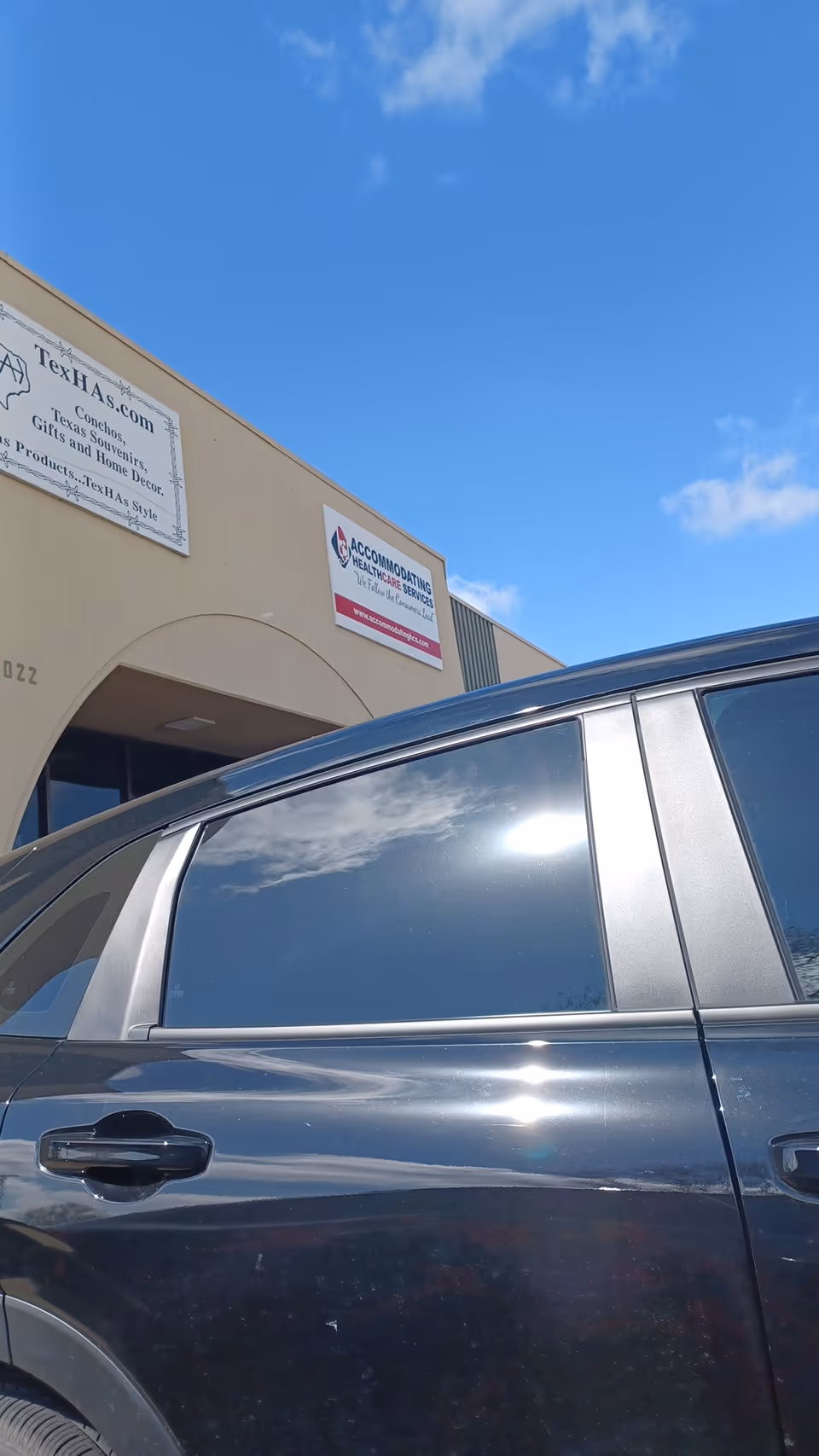 Exterior view of a facility with Accommodating Healthcare Services sign and a parked car.