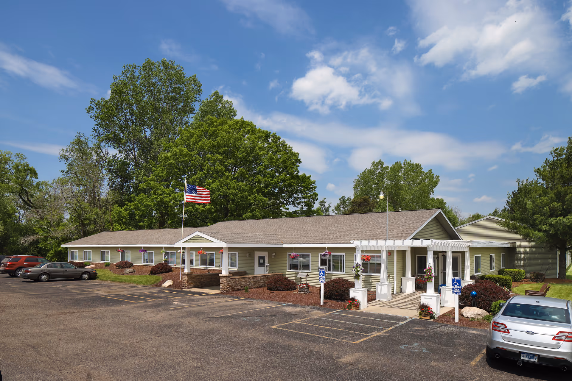 Single-story Americana Seniors facility with front entrance, parking, flagpole, and landscaping.