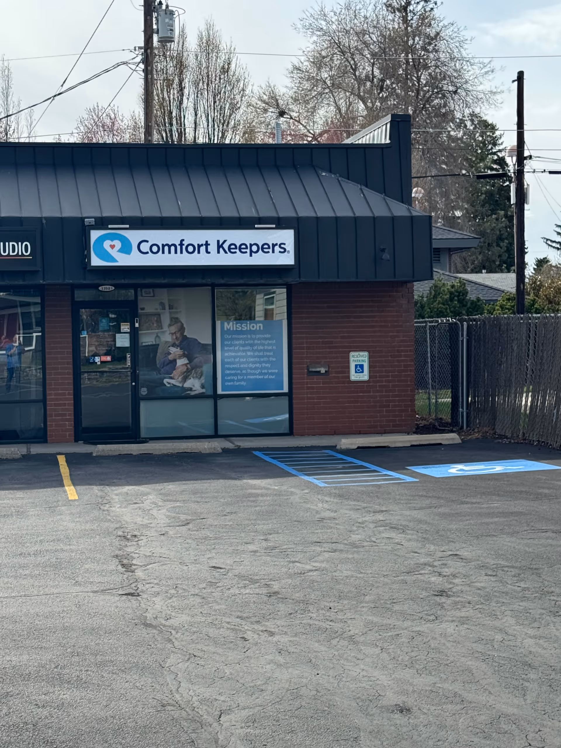Exterior view of Comfort Keepers storefront with blue sign and parking lot.