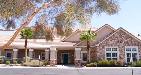 Brookdale East Tucson exterior with front entrance, stone facade, and palm trees.