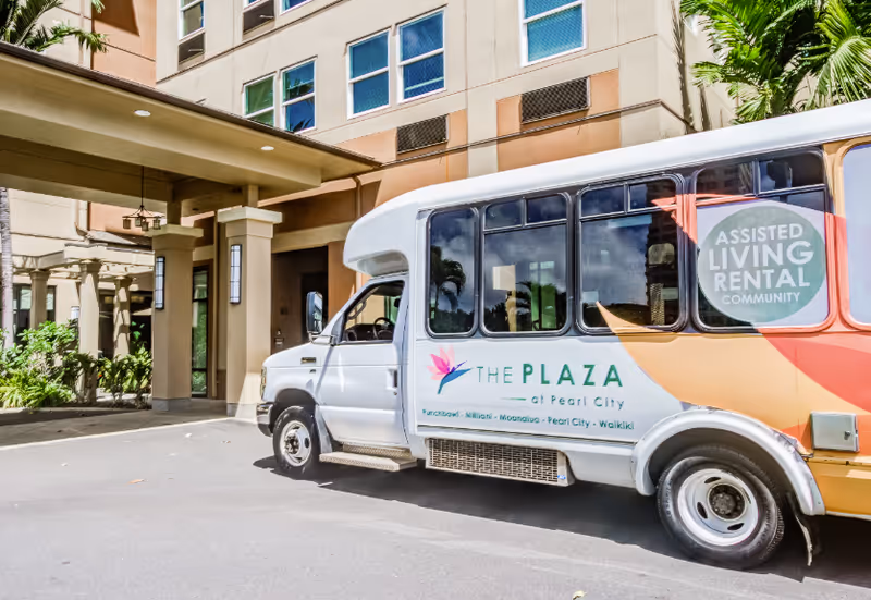 Exterior view of The Plaza at Pearl City with a shuttle bus parked in front.