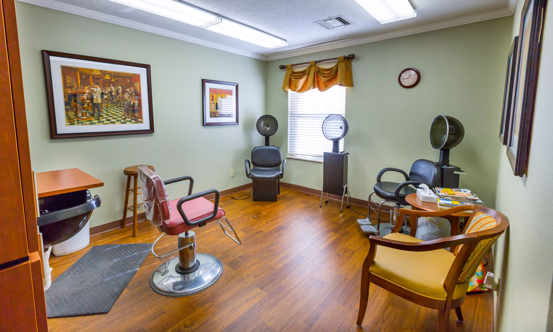 A small senior living facility hair salon with chairs, equipment, artwork, and magazines.