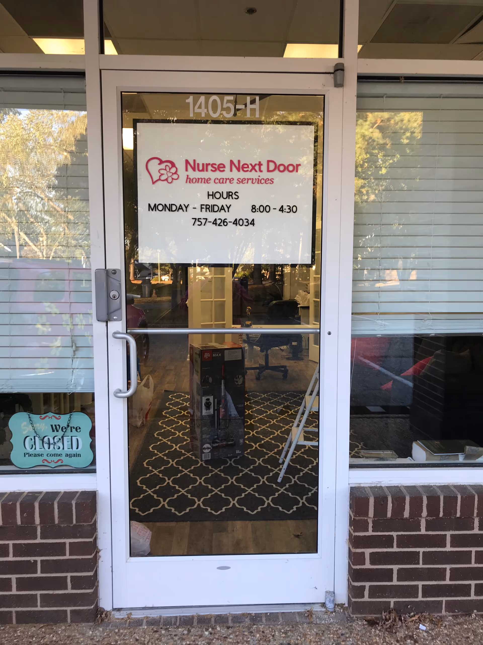 Entrance of Nurse Next Door Home Care Services with hours sign and rug.