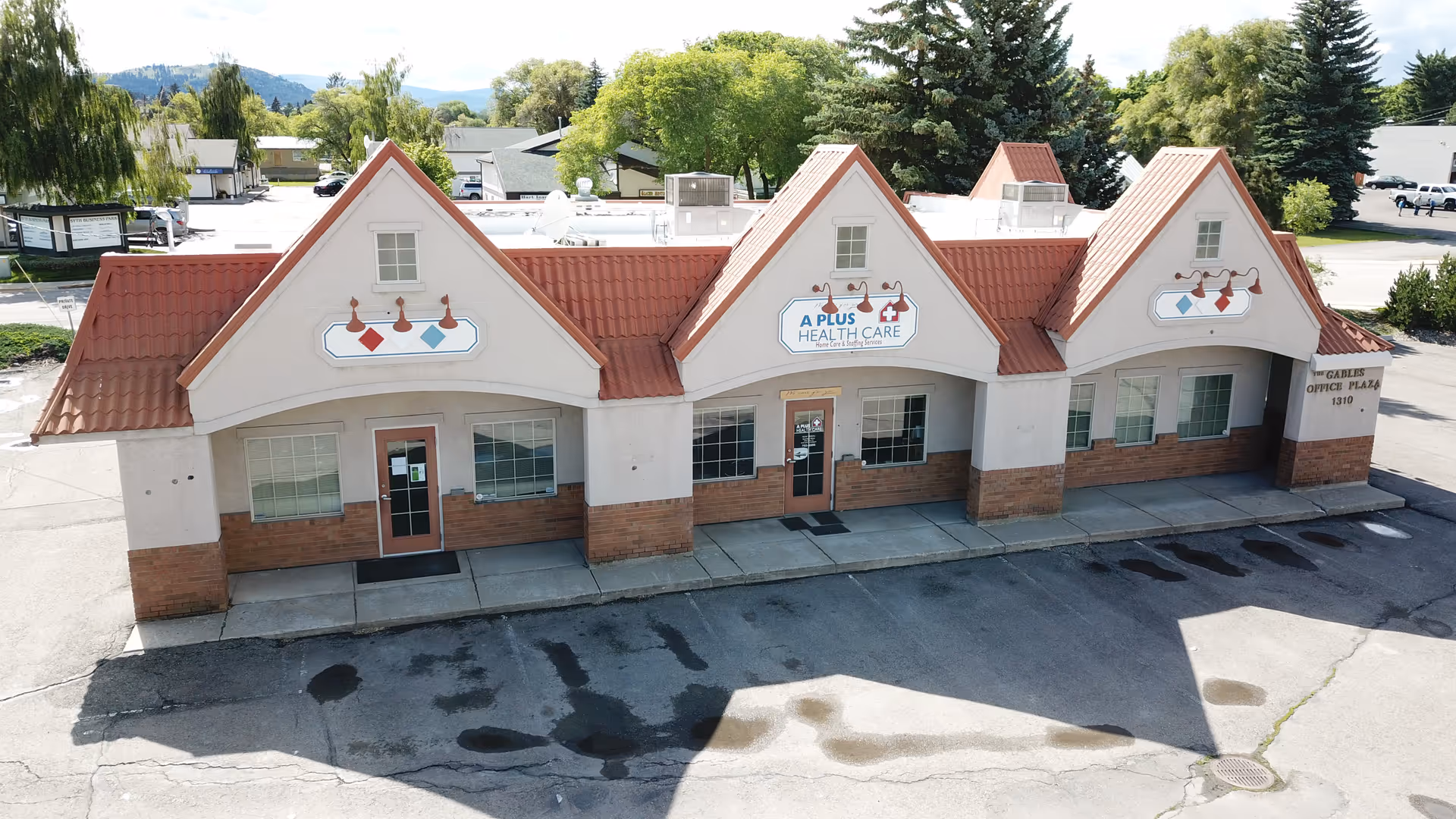 Exterior of A Plus Health Care building with three peaked red-tiled roofs.