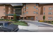 Front view of a brick senior living building with entrance and curved driveway.