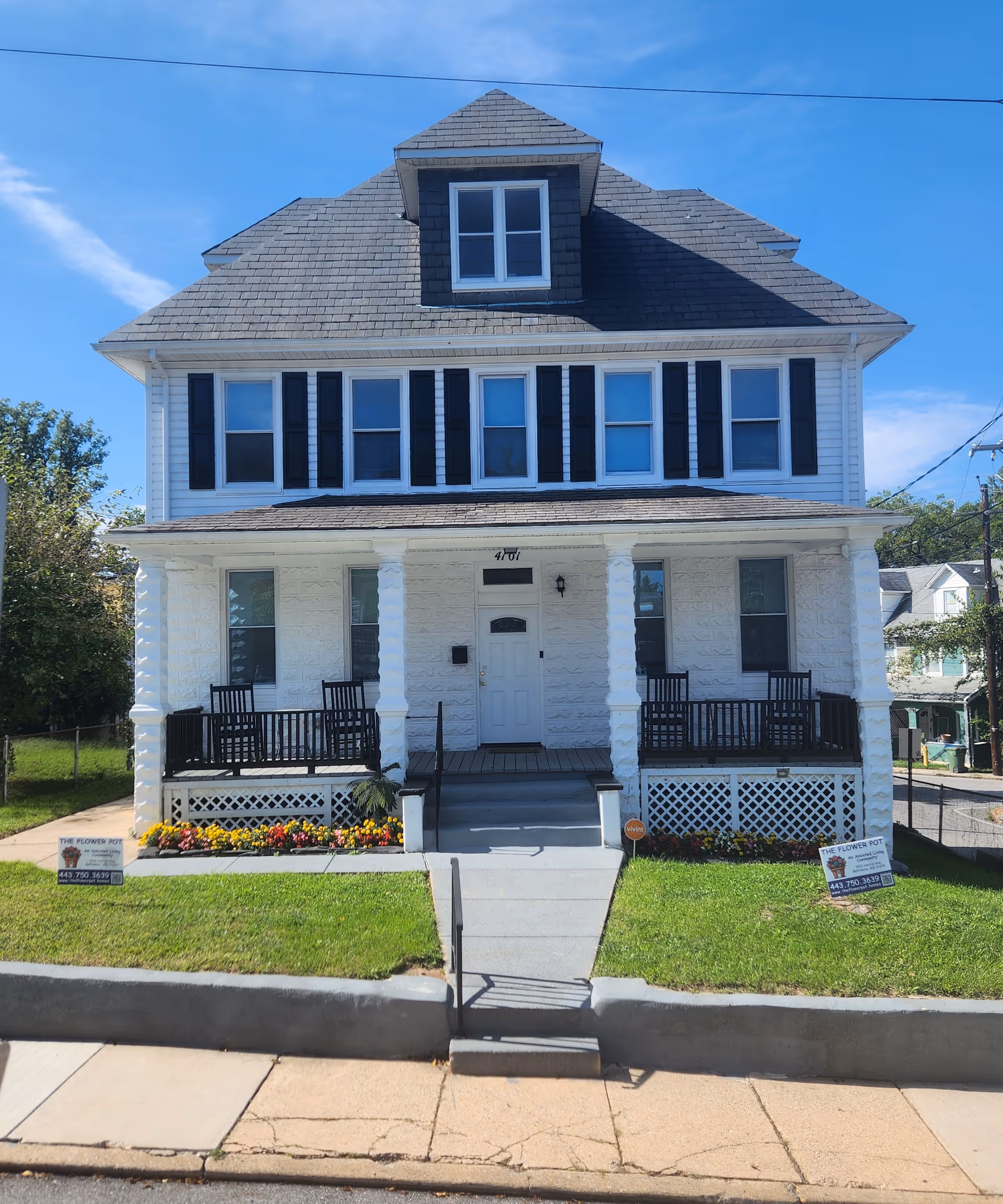 A two-story white building with a front porch, black shutters, and The Flower Pot signage.