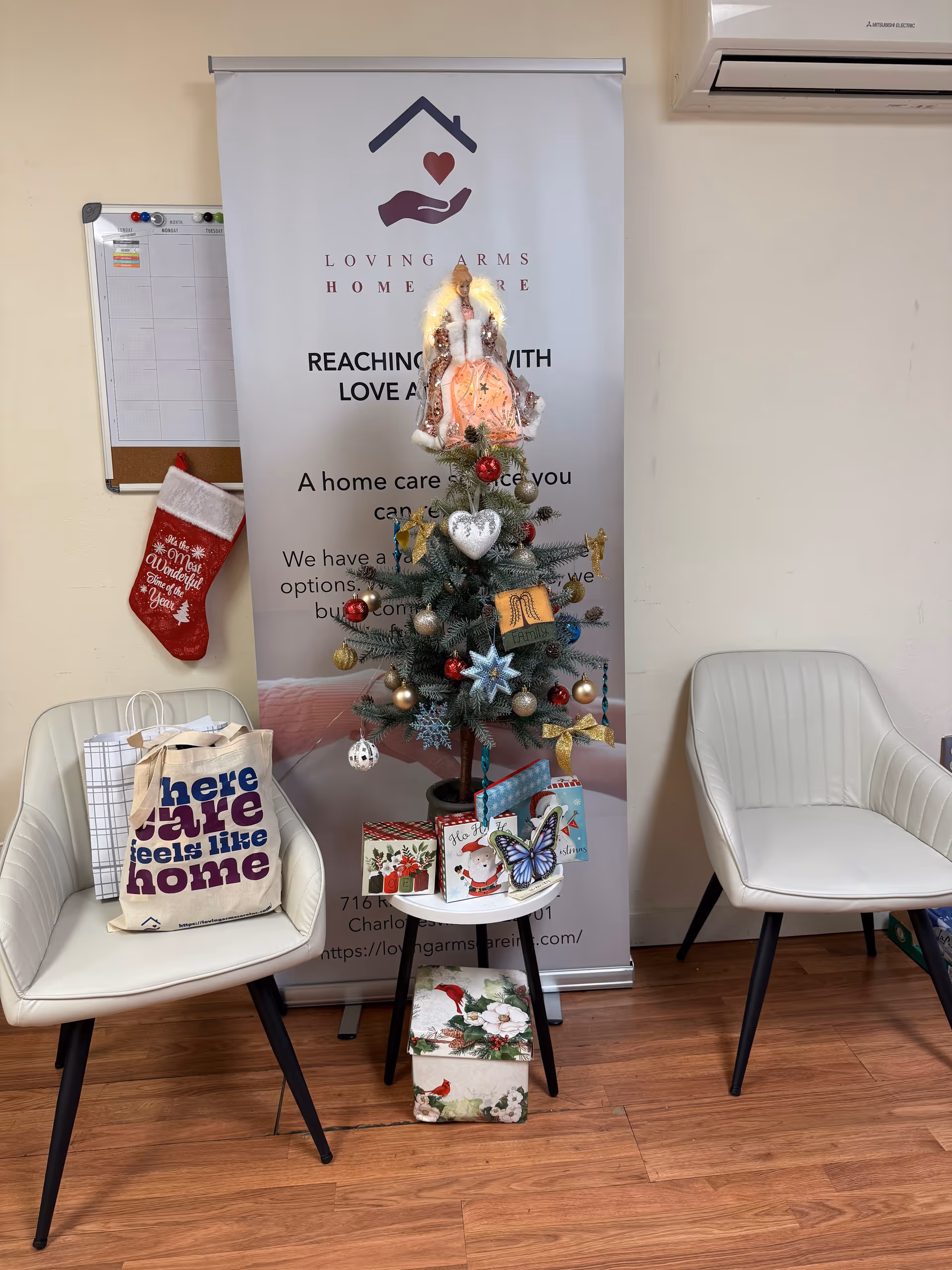 Indoor reception area featuring two white chairs, a decorated Christmas tree, and a banner.