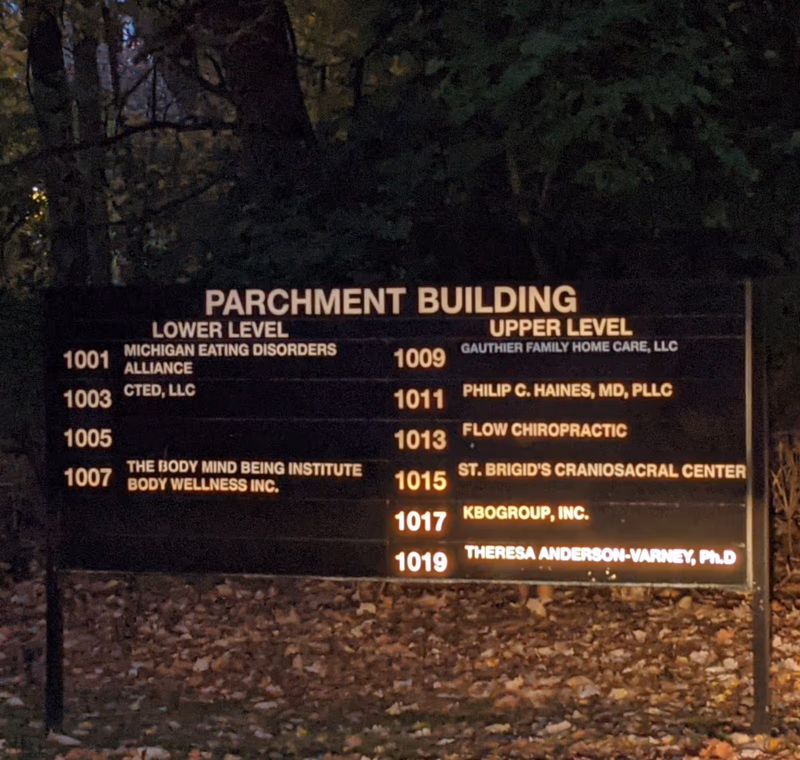 Nighttime exterior signboard listing tenants, including Gauthier Family Home Care, LLC.