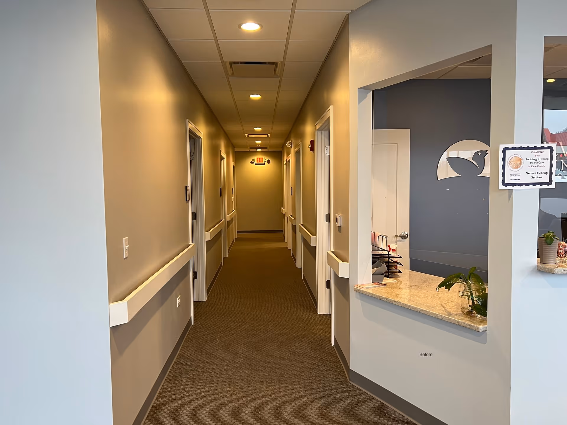 Narrow beige hallway inside a senior living facility with a reception window on the right.