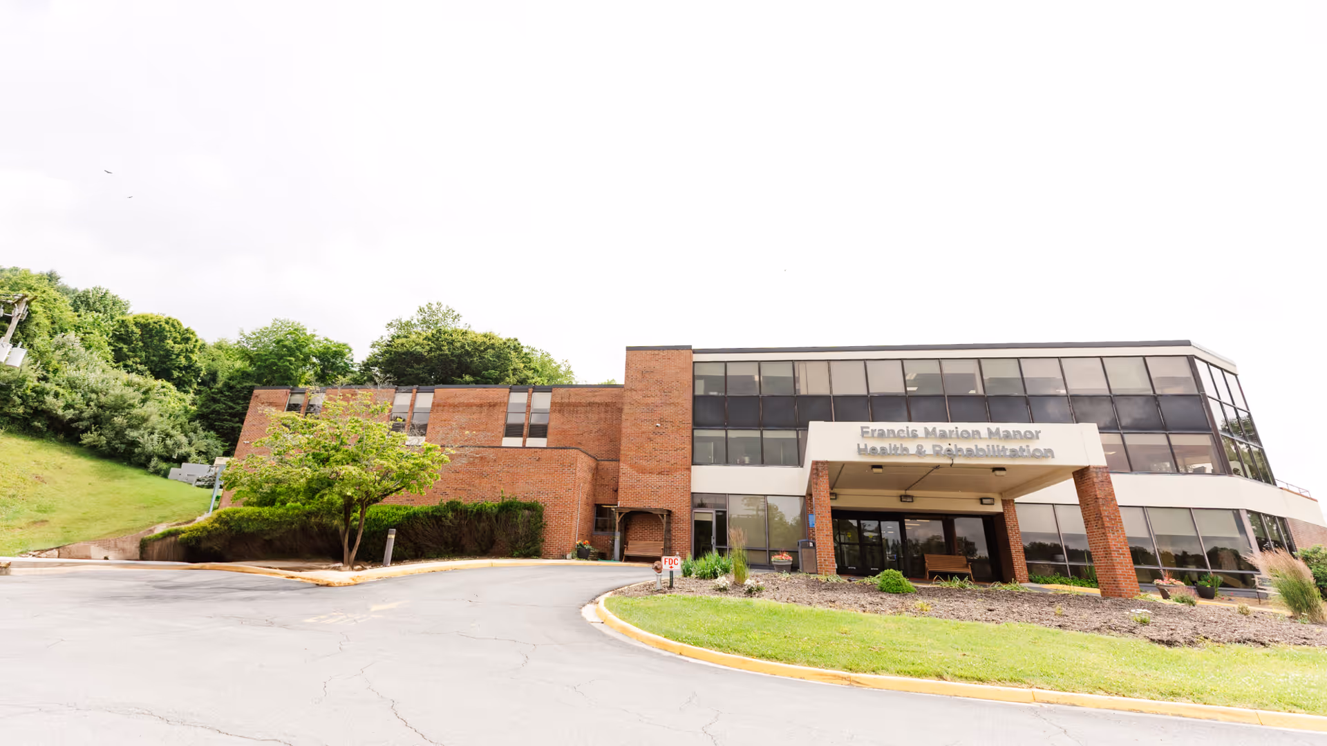 Exterior view of Francis Marion Manor Health & Rehabilitation with glass façade and entry.