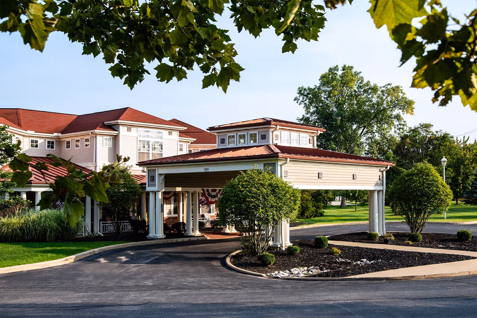 Entrance to a senior living campus with a porte-cochère and landscaped grounds.