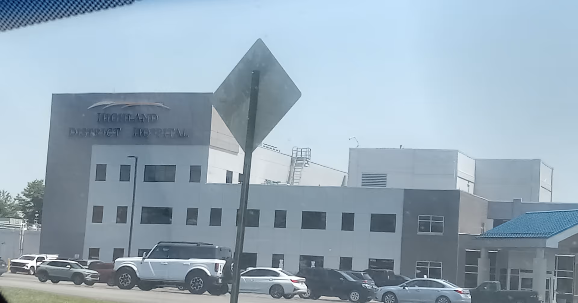 Exterior view of Highland District Hospital with parked cars and a modern facade.
