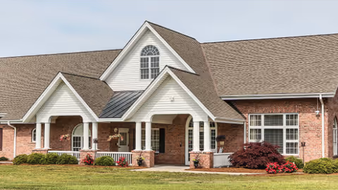 Brick hospice building with gabled roofs, covered entrance, and trimmed landscaping.