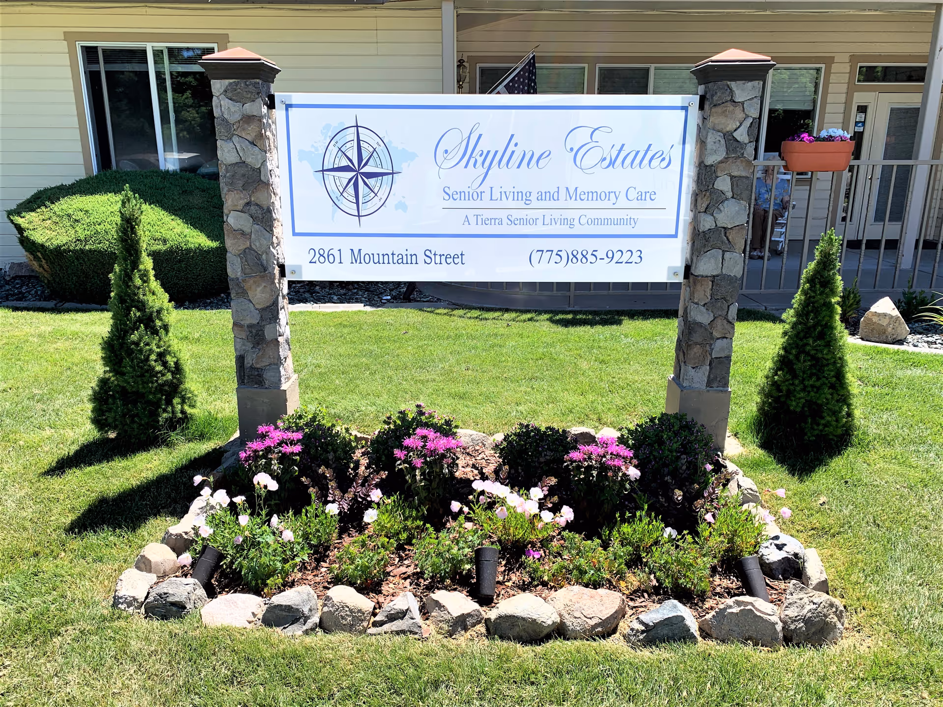 Front view of Skyline Estates sign with landscaped flower bed and building entrance.