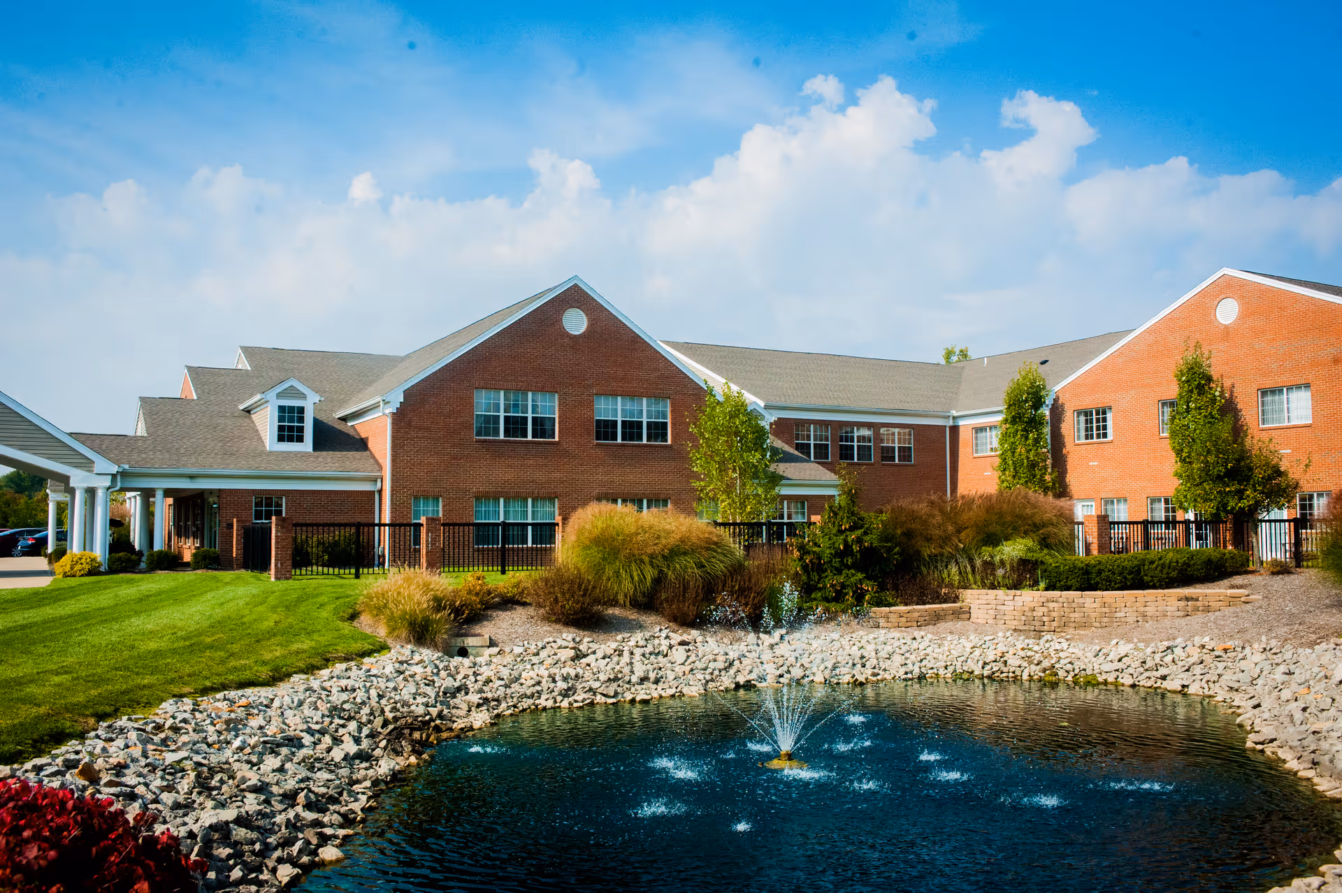 Brick Villaspring of Erlanger exterior with manicured lawn and pond.