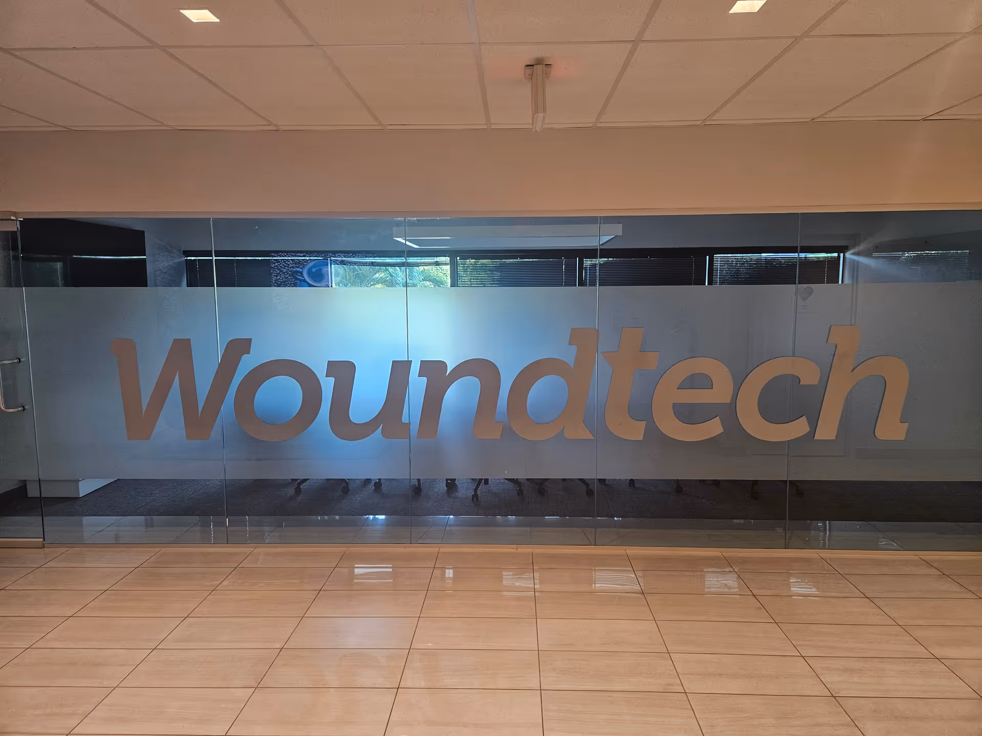 Large Woundtech logo on frosted glass divider inside a modern facility lobby.