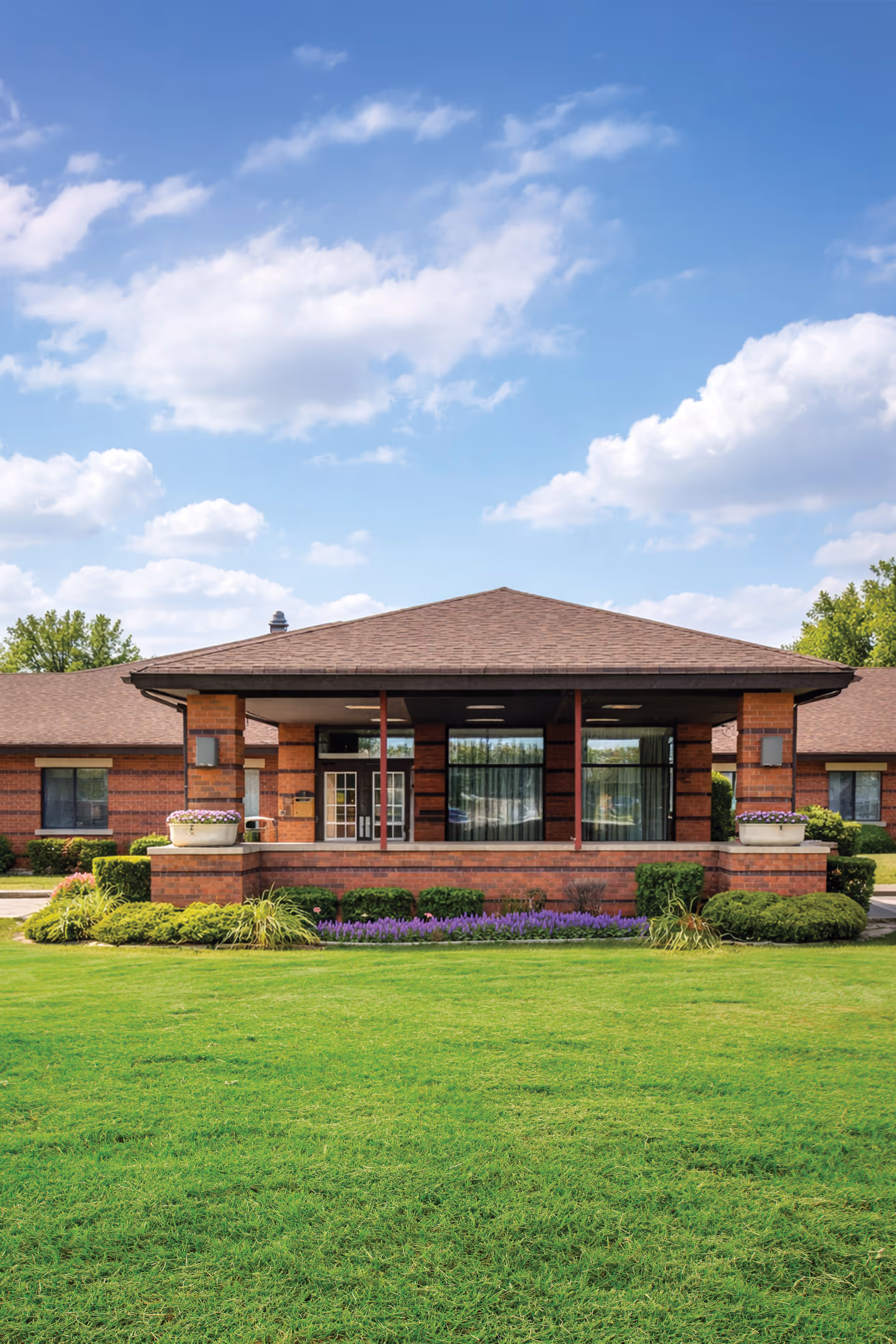 Front entrance of a brick senior living facility with manicured lawn.
