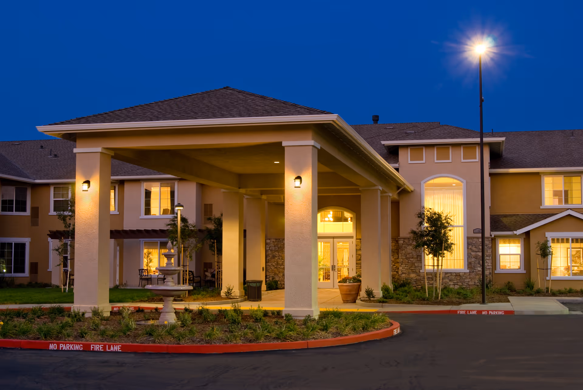 Exterior view of Prestige Assisted Living at Manteca, illuminated entrance under a covered porte-cochère.